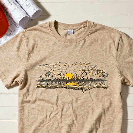 Beige t-shirt with mountain and sun graphic on a wooden surface with hard hat, boots, and gloves.